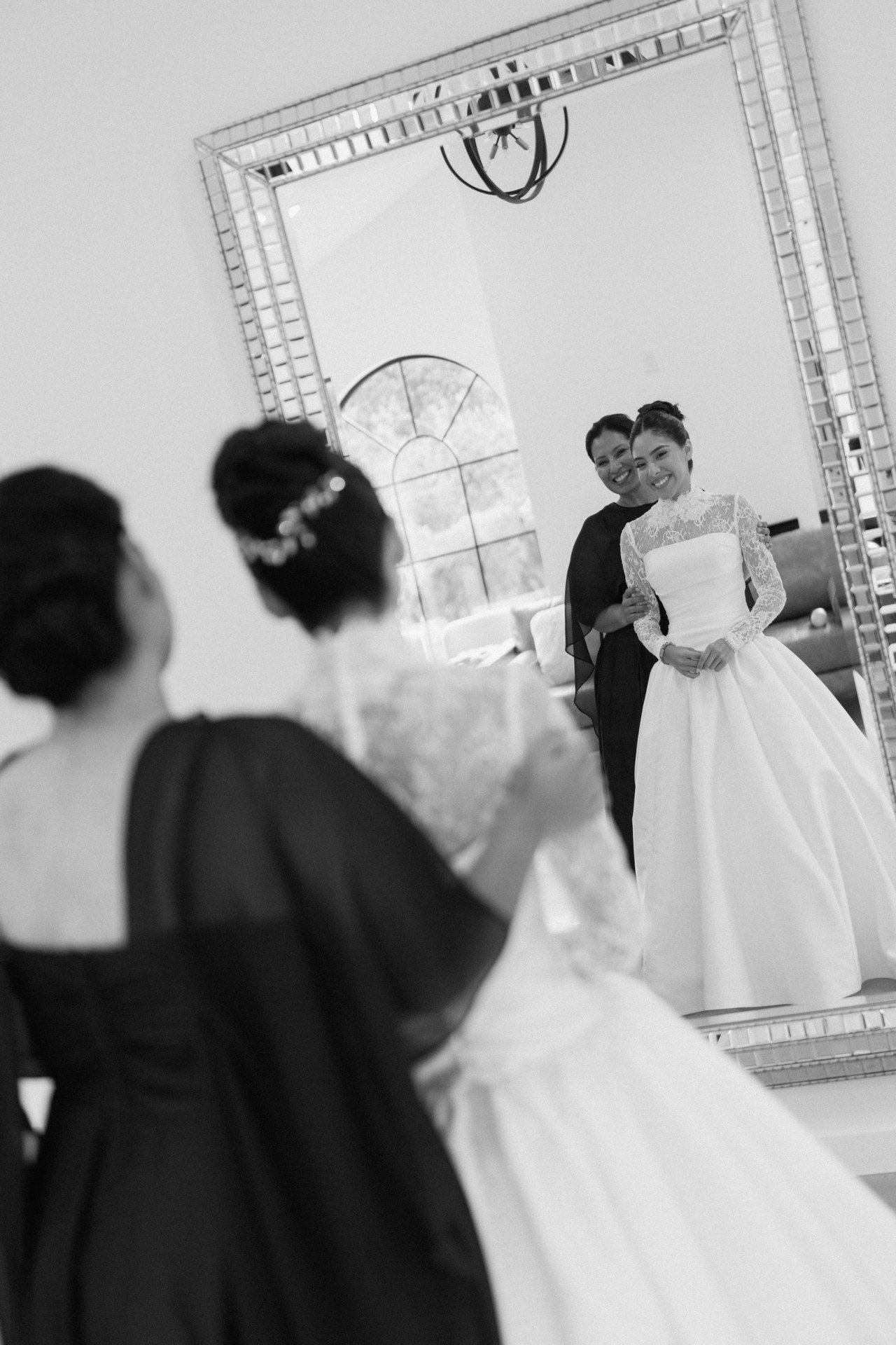 Black-and-white reflection of a bride getting ready with a companion.