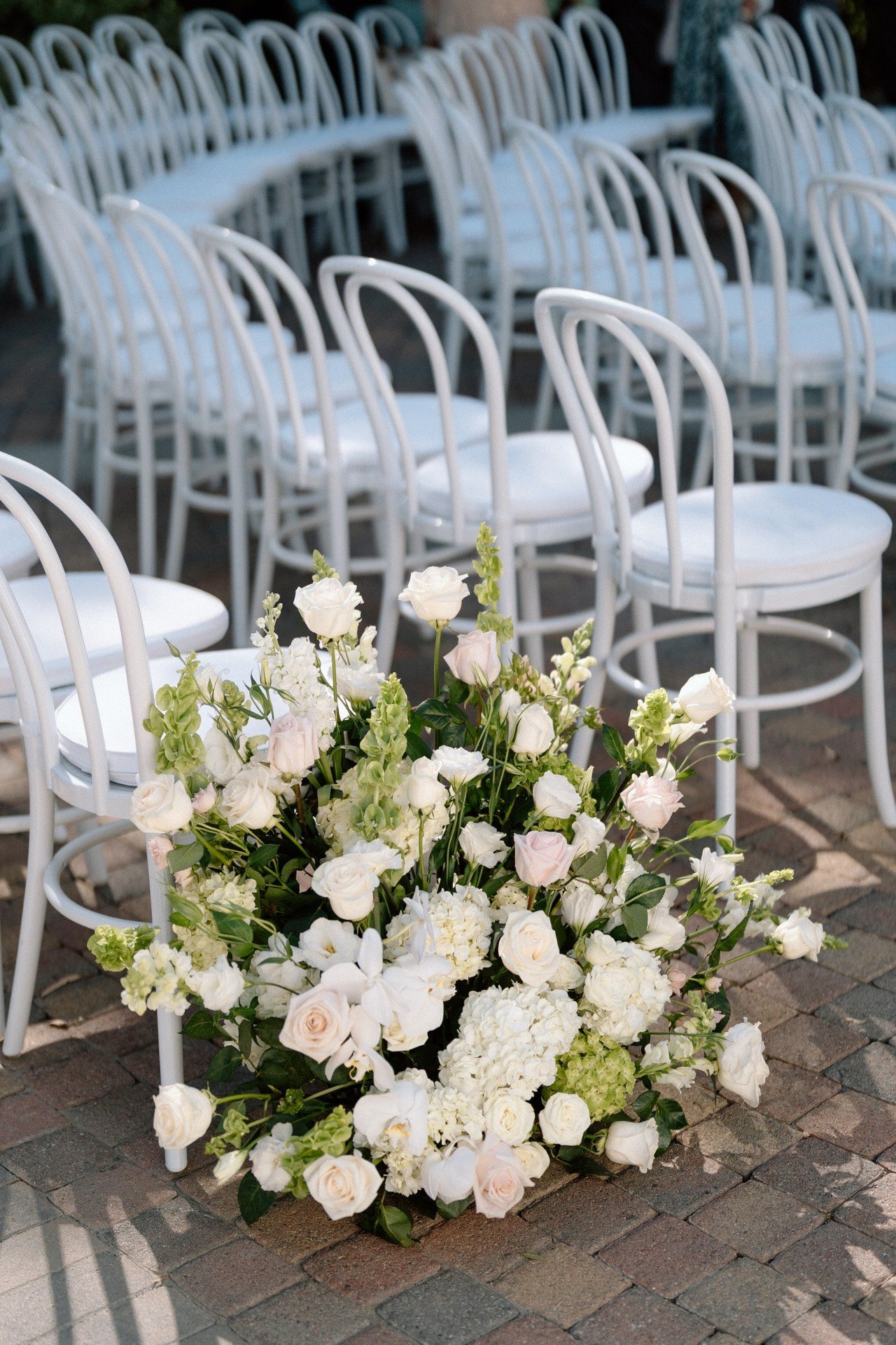 White flowers arranged beside rows of ceremony chairs.