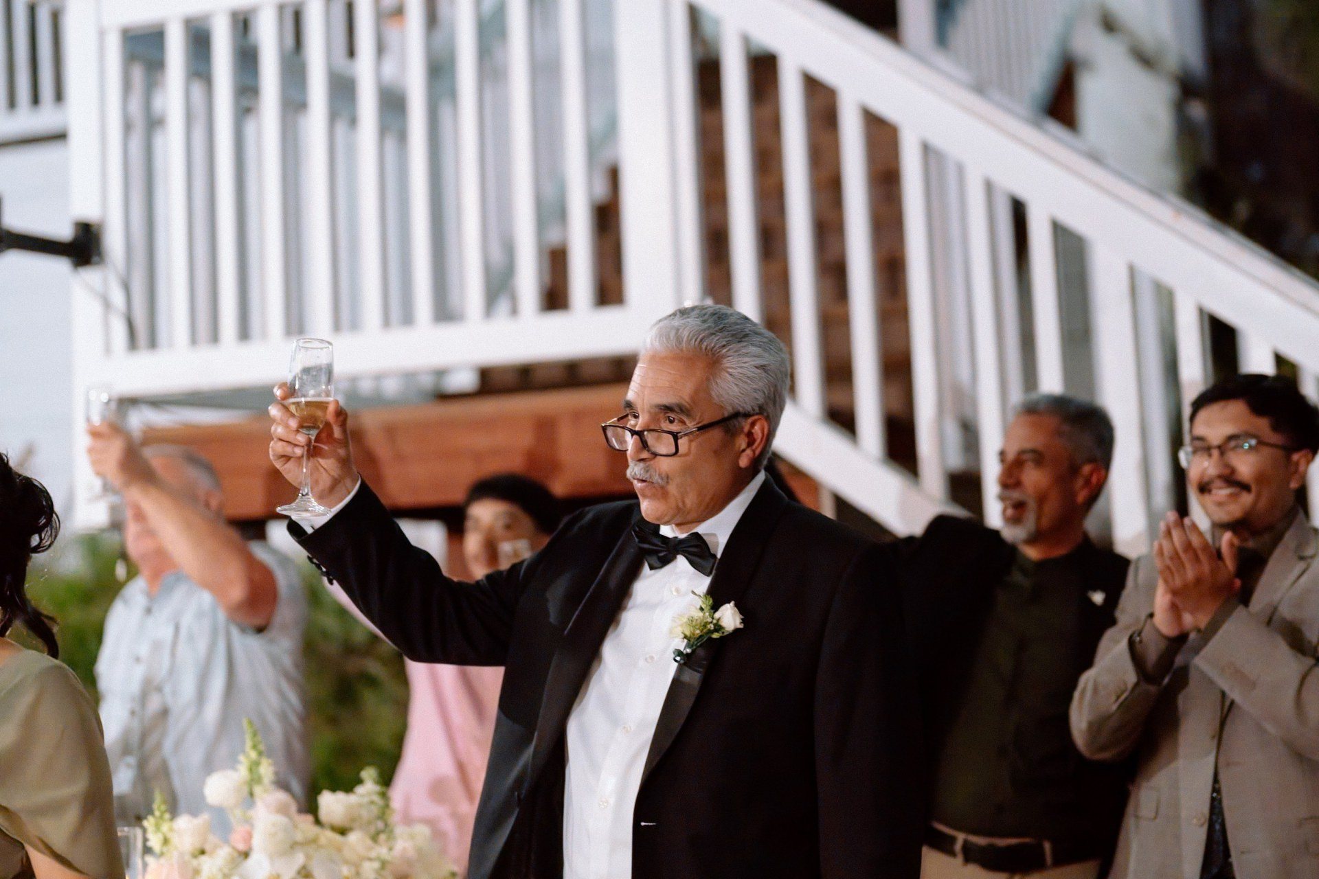 Guests raising their glasses during an outdoor reception toast.