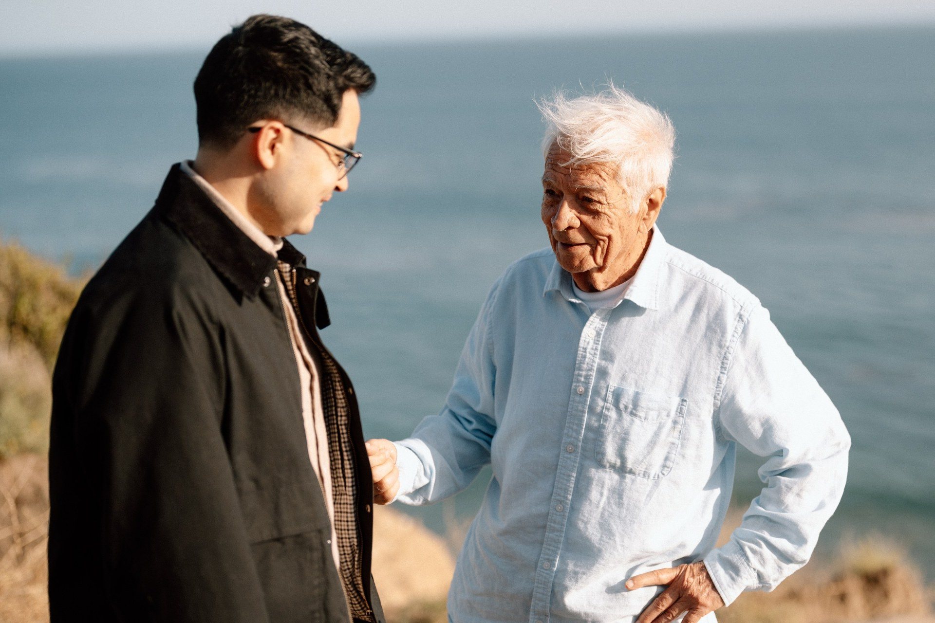A man sharing a smile with a guest beside the ocean.