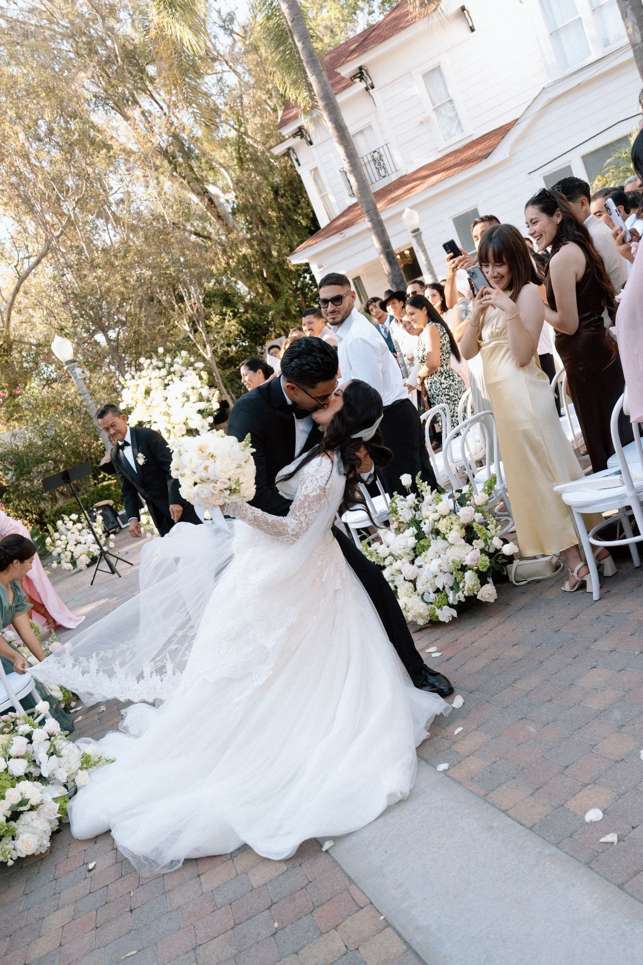 Newlyweds sharing a dip and kiss in the ceremony aisle.