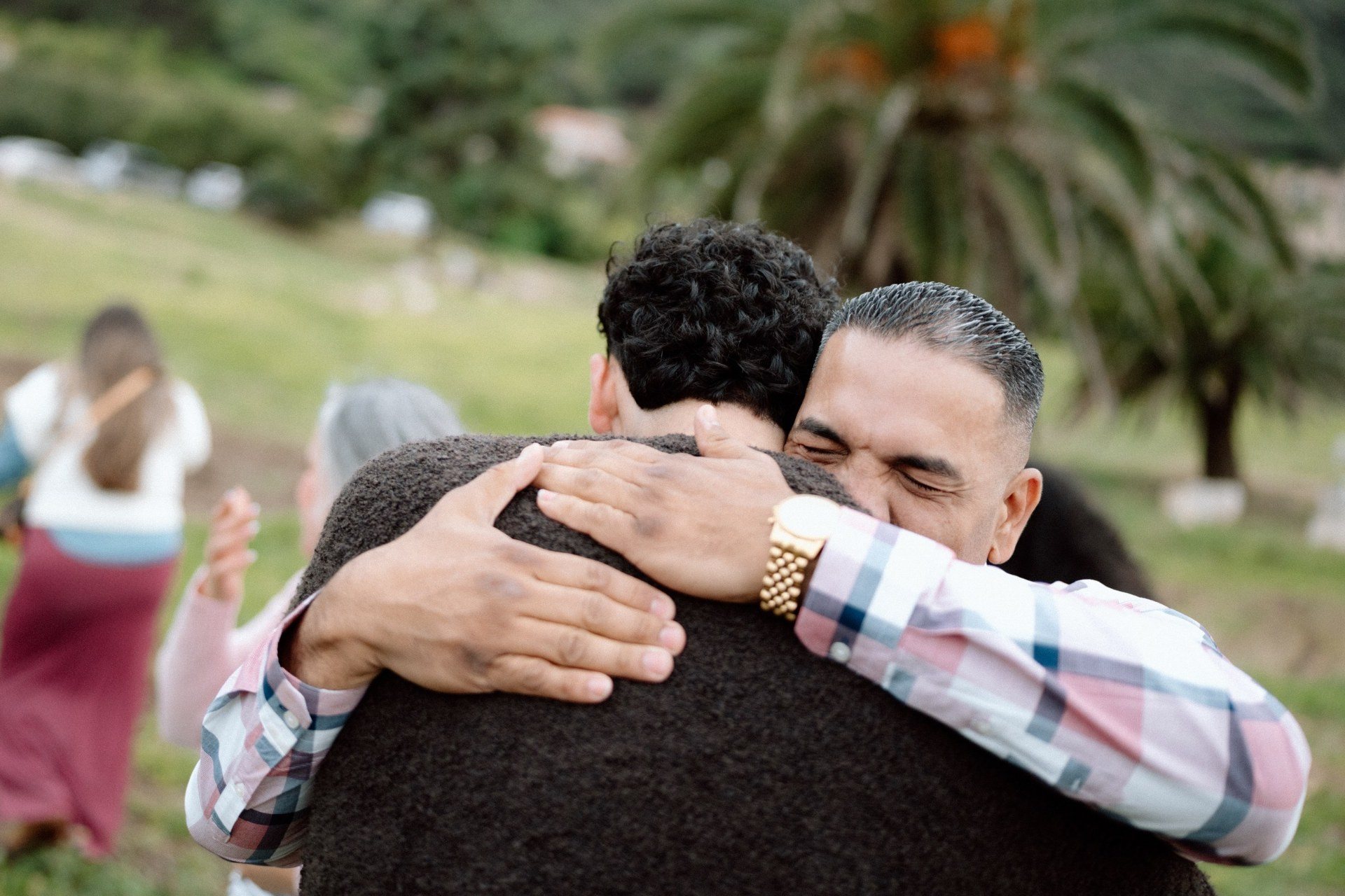 Two guests sharing an emotional embrace outdoors.