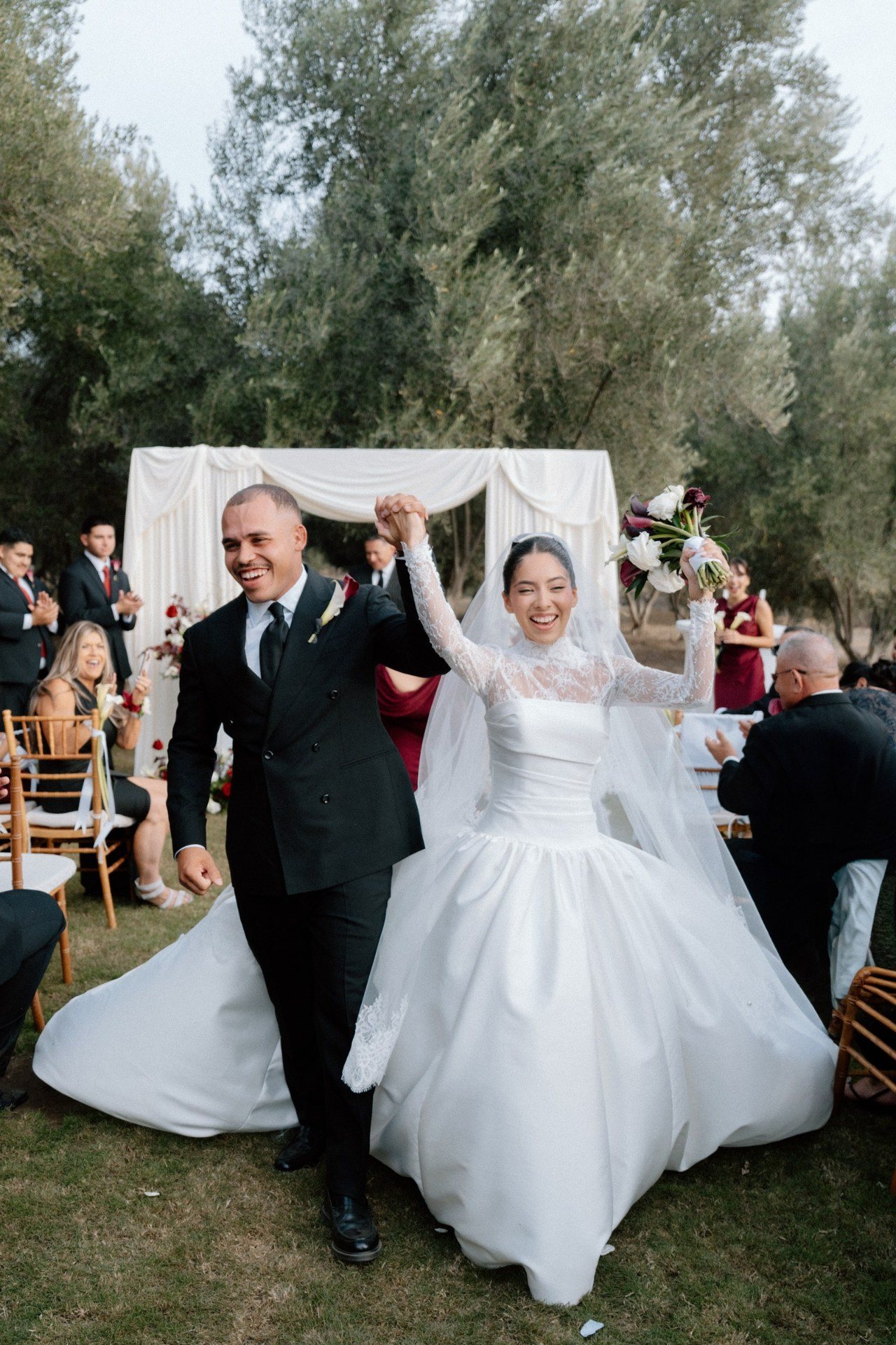 Newlyweds raising their joined hands as they leave the ceremony.