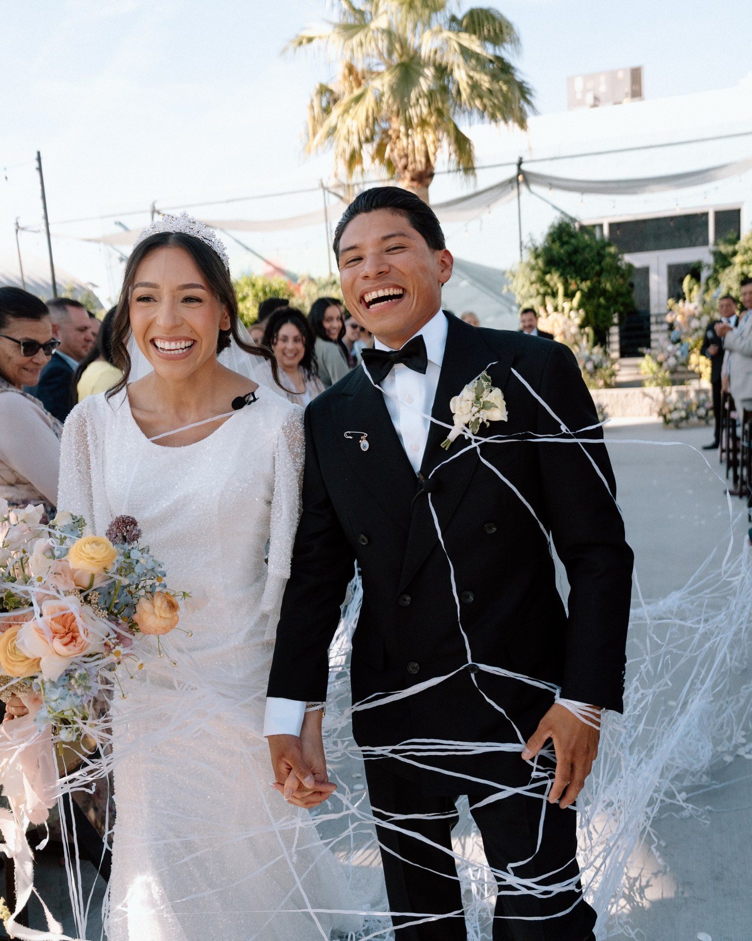 Newlyweds smiling as they walk through celebratory streamers.