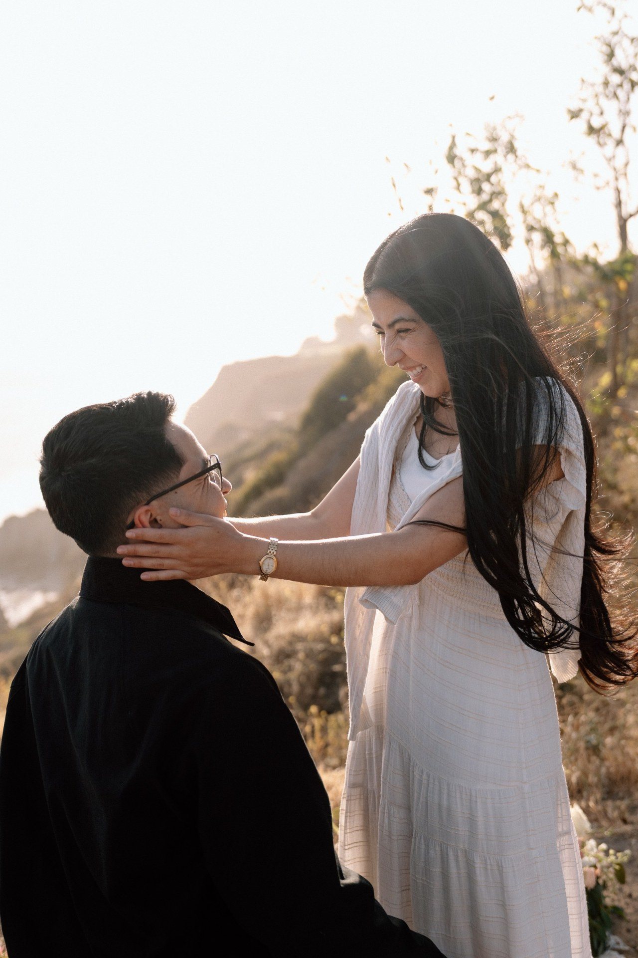 A woman smiling at her partner while holding his face.