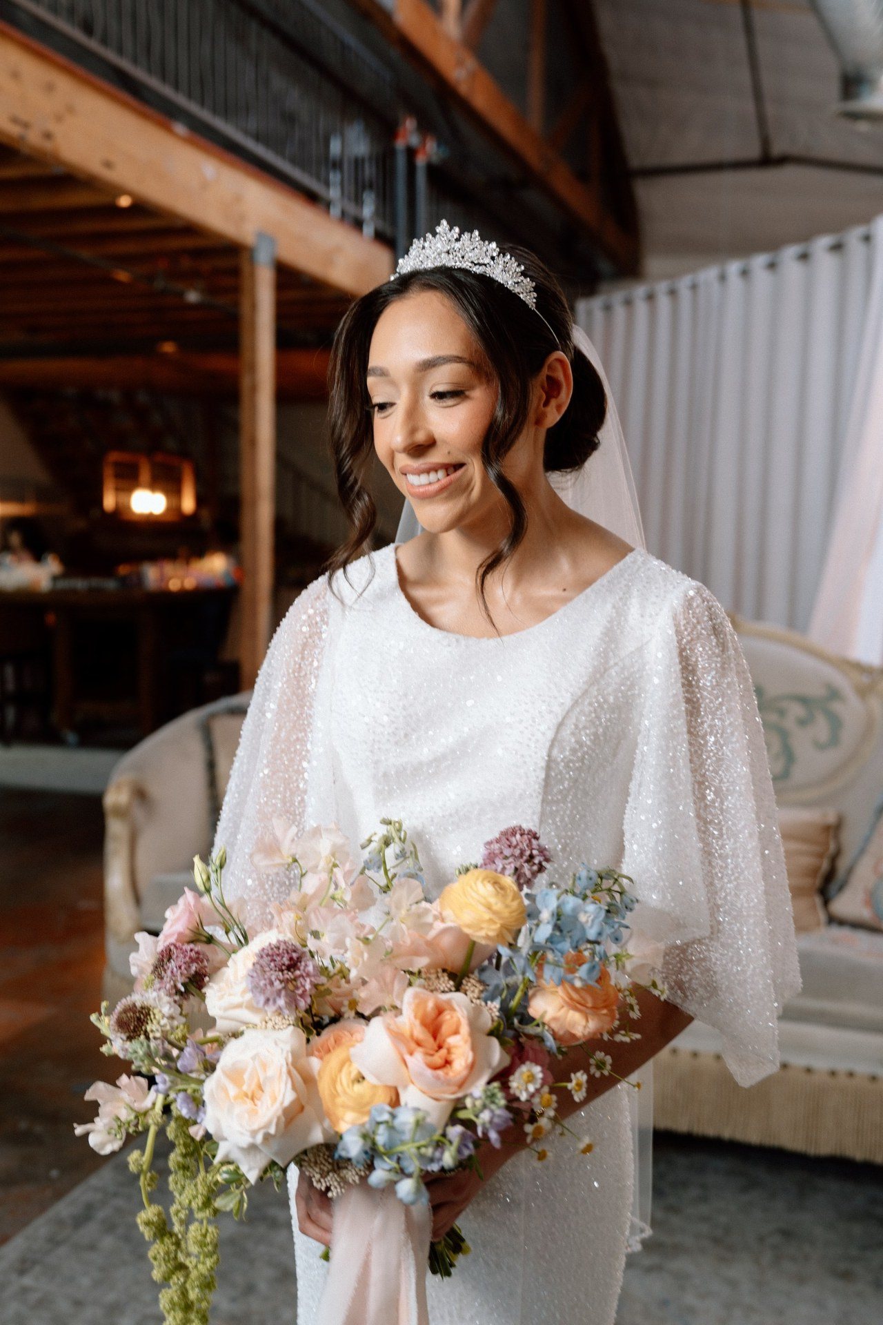 Bride holding a colorful bouquet in soft window light.